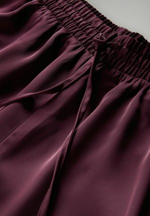Bordeaux Satin-Shorts mit elastischem Bund und Kordelzug. Der Stoff hat eine glatte Textur und fließt sanft.