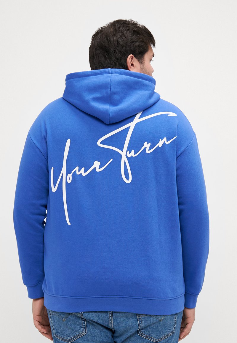 Felpa blu realizzata in tessuto misto cotone, con testo in corsivo bianco "Your Turn" sulla schiena. Include un cappuccio e polsini a coste.