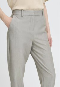 Světle šedé kalhoty na míru s jemným proužkovaným vzorem, bez záhybů vpředu, s bočními kapsami a hladkou texturou.