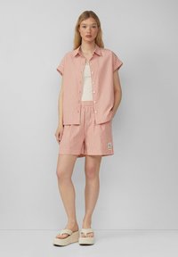 Rood en wit gestreept T-shirt met korte mouwen en bijpassende shorts; de stof heeft een lichte textuur, met een elastische tailleband en een logopatch.
