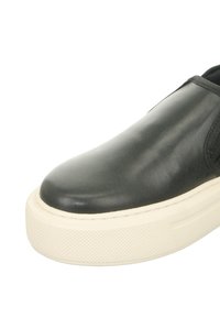 Black leather slip-on sneaker with a rounded toe, featuring a textured white rubber sole and elastic side accents for a snug fit.