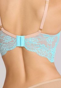 Koronkowy biustonosz z kwiatowym wzorem w jasnym niebieskim kolorze, nude ramiączka i ozdobny zapięcie z tyłu. Gładka tekstura z misternymi detalami.