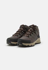 Brown hiking shoes with a synthetic upper, textured accents, and a rubber sole. Features metal eyelets for lacing and a rugged design.