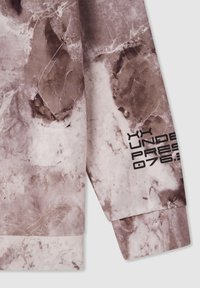 Top a maniche lunghe in tessuto beige e marrone con motivo marmorizzato, caratterizzato da testo grafico nero sulla manica e orlo a polsino.
