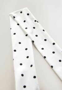 Weiße Stretch-Leggings mit einem Muster aus schwarzen Punkten. Glatte Textur und elegantes Design, ideal für die Freizeit.