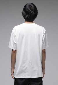 T-shirt ample en coton blanc à manches courtes et col rond, avec une texture lisse et un design épuré, vue de dos.