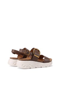 Sandali in pelle marrone con due ampie cinghie, grande dettaglio con fibbia dorata e una suola bianca spessa con design testurizzato. Sottopiede in sughero per il massimo comfort.