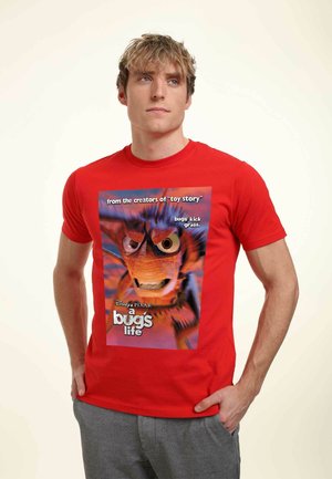 Rød bomulds T-shirt med grafisk tryk af en karakter fra "Bugs liv" med tekst i hvidt og sort. Kort ærmer, rund halsudskæring.