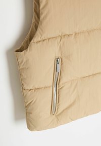 Beżowa kamizelka puchowa wykonana z lekkiego materiału, z zamykaną na zamek kieszenią i gładką teksturą. Bez rękawów, prosty design.