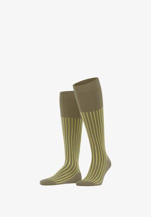 Chaussettes montantes en matériau doux et flexible, avec une base vert olive et des rayures verticales jaune vif.