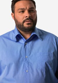 Camicia azzurro chiaro con bottoni realizzata in tessuto morbido, con colletto classico, taschino frontale e un leggero motivo testurizzato.