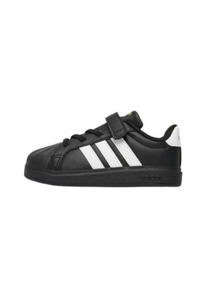 Sneaker nera low-top con strisce bianche, lacci e una fascia in velcro, con suola nera e tallone bianco.