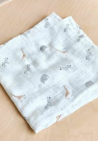 Ľahká, biela mušelínová tkanina s jemnou textúrou. Obsahuje šedé zebry, žirafy a hravé vzory mesiacov v pastelových farbách.