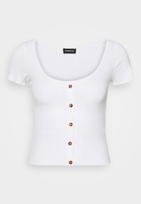 Vit ribbad kortärmad topp med en bred rundad halsringning och en rad av sex faux sköldpaddsknappar framtill.