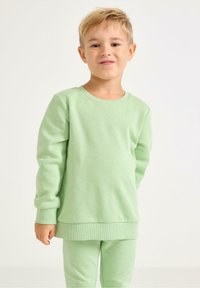 Hellgrüner Sweatshirt aus weichem Stoff, mit Rundhalsausschnitt und Rippbündchen, kombiniert mit passenden Hosen, die ein abgestimmtes Outfit ergeben.