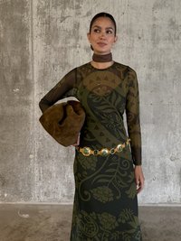 Dlhý rukáv šaty v tmavozelenej farbe s kvetinovými a geometrickými vzormi. Zvýraznené zlatým opaskom a doplnené hnedou taškou.