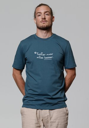 Teal katoenen T-shirt met korte mouwen, met witte tekst die leest: "Früher war alles beter." Effen kleur, ronde halslijn.