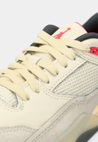 Μπεζ αθλητικό παπούτσι με άνω μέρος από πλέγμα και δέρμα, κρέμα κορδόνια, καουτσούκ σόλα και κόκκινο λογότυπο κοντά στον αστράγαλο. Διαθέτει μαλακή επένδυση στον αστράγαλο.