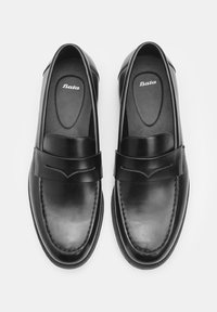 Mocassins en cuir noir avec une texture lisse, sangle décorative sur le dessus et détails de couture subtils. Logo de la marque visible sur les semelles intérieures.