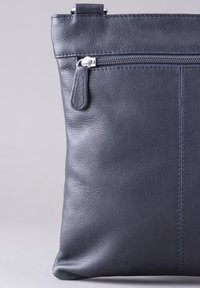 Leather crossbody bag in dark navy. Features a zipper closure, smooth texture, minimal stitching detail, and a sleek, rectangular shape.