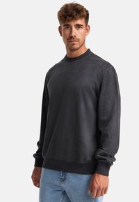Mørkegrå sweatshirt lavet af blødt stof, har en rund halsudskæring og lange ærmer med ribbede manchetter og kant. Minimalistisk design.