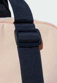 Borsone con un corpo in tessuto rosa e una tracolla navy texturizzata. Presenta una fibbia in plastica nera per la regolazione e il fissaggio sicuro.