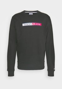 Svart sweatshirt med långa ärmar, ribbad mudd och nederkant, med en färgglad "TOMMY JEANS"-logotyp över bröstet i vitt, röd och blå.