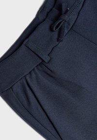 Marineblauwe sportshorts gemaakt van zachte, rekbare stof met een trekkoord tailleband, voorzien van plooien en een gladde textuur.
