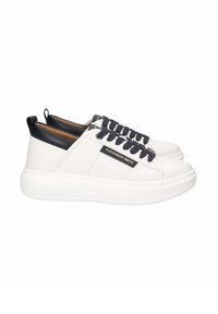 Zapatillas de cuero blancas con punta redonda, cordones azul oscuro y detalles en el talón. Cuentan con una suela de goma y un logo de la marca en el lateral.