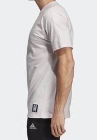 Lichtgrijze T-shirt met korte mouwen, gemaakt van katoen, met een ronde hals en een kleine logopatch aan de zoom. Soepele textuur, relaxte pasvorm.