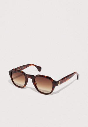 Óculos de sol tartaruga com um formato quadrado, lentes degradê e um detalhe em logotipo dourado na haste. Material plástico liso e brilhante.