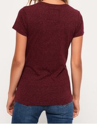 Camiseta corta de manga en burdeos con escote redondo y una textura suave. Presenta un corte relajado y un dobladillo trasero ligeramente más largo.