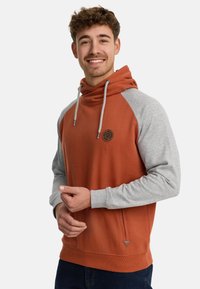 Hoodie met een oranje lichaam en grijze mouwen, met koordjes, een voorkantzak en een logo op de borst. Gemengd katoen.