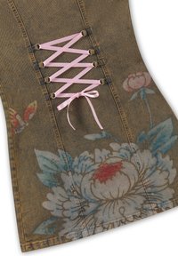 Tissu en denim avec de grands motifs floraux peints et un ruban de satin rose lacé à travers des œillets métalliques en motif croisé.