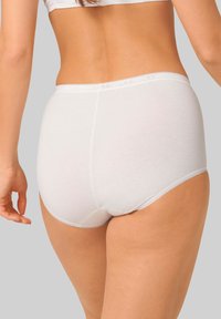 Slip di cotone bianco con una texture liscia, vita alta e un delicato dettaglio di rifinitura lungo le aperture delle gambe e la cintura.
