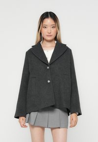 Veste en mélange de laine grise avec un grand col, deux poches avant et boutons ronds argentés. Présente une coupe décontractée et une texture lisse.
