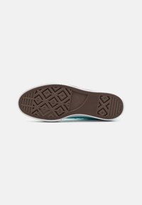 Brown rubber sneaker outsole with a herringbone pattern, white side edge, and turquoise midsole. Features a textured grip for traction.