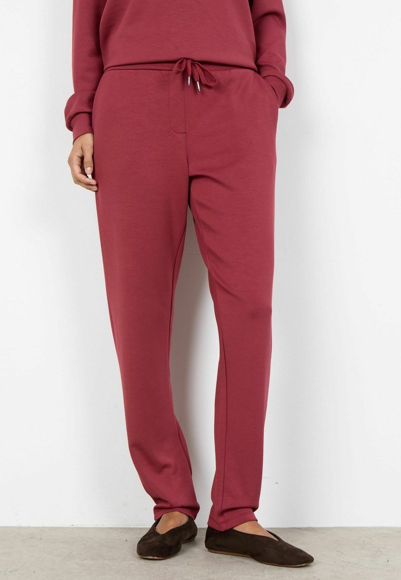 Bordowe spodnie dresowe wykonane z miękkiego materiału, wyposażone w regulowany sznurek w talii, boczne kieszenie oraz zwężany krój nogawek.