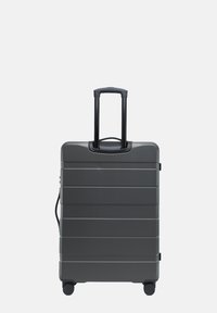 Šedý pevný kufr s vertikálními pruhy, vysouvací černá rukojeť a čtyři kolečka pro snadnou manipulaci. Kompaktní, obdélníkový design.