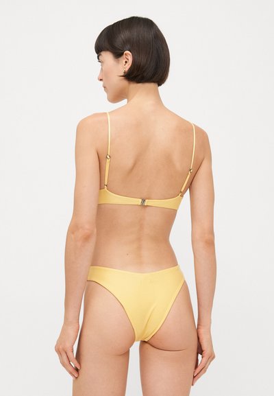 Dzeltena bikini komplekts ar vienkāršu dizainu, plānām regulējamām siksnām un aizdari aizmugurē. Mīksta, gluda tekstūra ar minimālu pārklājumu.
