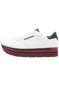 Sneaker bianco in pelle con punta rotonda, suola piattaforma a righe nere e rosse, e un accento in pelle marrone texturizzata sul tallone. Perforazioni dettagliate visibili.
