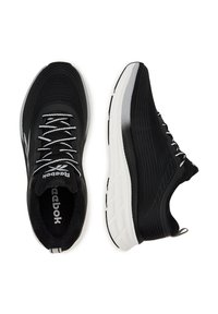 Fekete sportcipők textúrázott hálós felsőrésszel, fehér fűzőkkel és vastag fehér talppal. Az oldalán logó és díszvonalak találhatók.