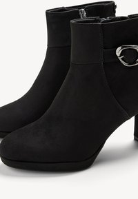 Svarta mocka ankelstövlar med rund tå, klack av blockmodell och sidodragkedja; har en silvermetallaccent på det övre bandet.