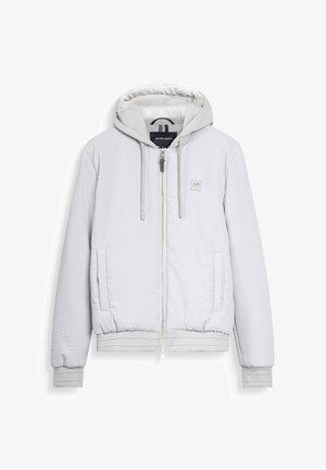Veste à capuche zippée en quilt léger gris clair avec cordons de serrage, deux poches avant, des poignets côtelés et un petit logo AM brodé sur la poitrine.