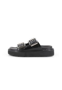 Sandalias negras con dos correas de hebilla, una parte superior lisa y una suela gruesa y texturizada. Los acentos plateados en las hebillas realzan el diseño.