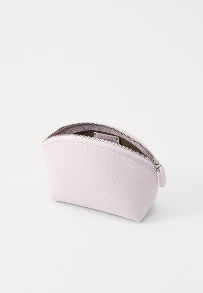 Neceser de color púrpura claro con exterior de cuero texturizado, forma curva y cierre de cremallera plateado. El interior está forrado con una tela sólida.