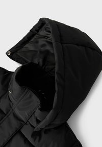 Giacca a vento nera con cappuccio, finitura lucida, chiusura con zip e motivo trapuntato. L'interno è foderato con materiale morbido.