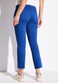Blaue Stretchpants mit normaler Taille, figurbetonter Form und  cropped Länge. Mit Gesäßtaschen und minimalistischen Nähten.