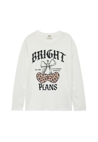 Hvid langærmet skjorte med sort tekst "BRIGHT PLANS" og et grafisk motiv af leopardprint-kirsebær med en sløjfe. Blødt bommaterials.
