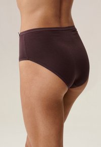 Ciemnobrązowe figi z wysokim stanem o gładkiej fakturze. Posiadają elastyczną talię i gładkie krawędzie, zapewniając pełne pokrycie.